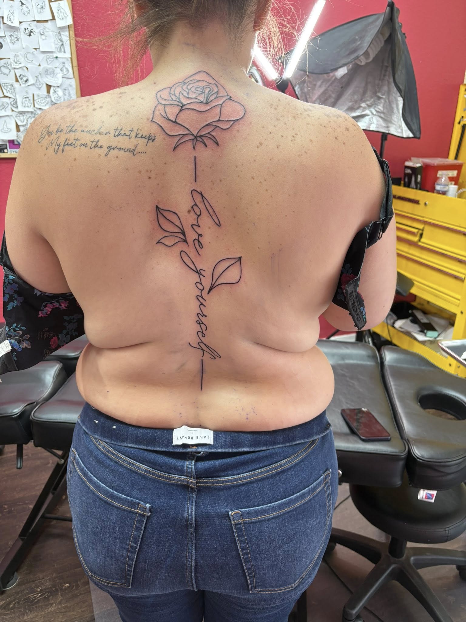 Fine line rose spine tattoo with Love Yourself script