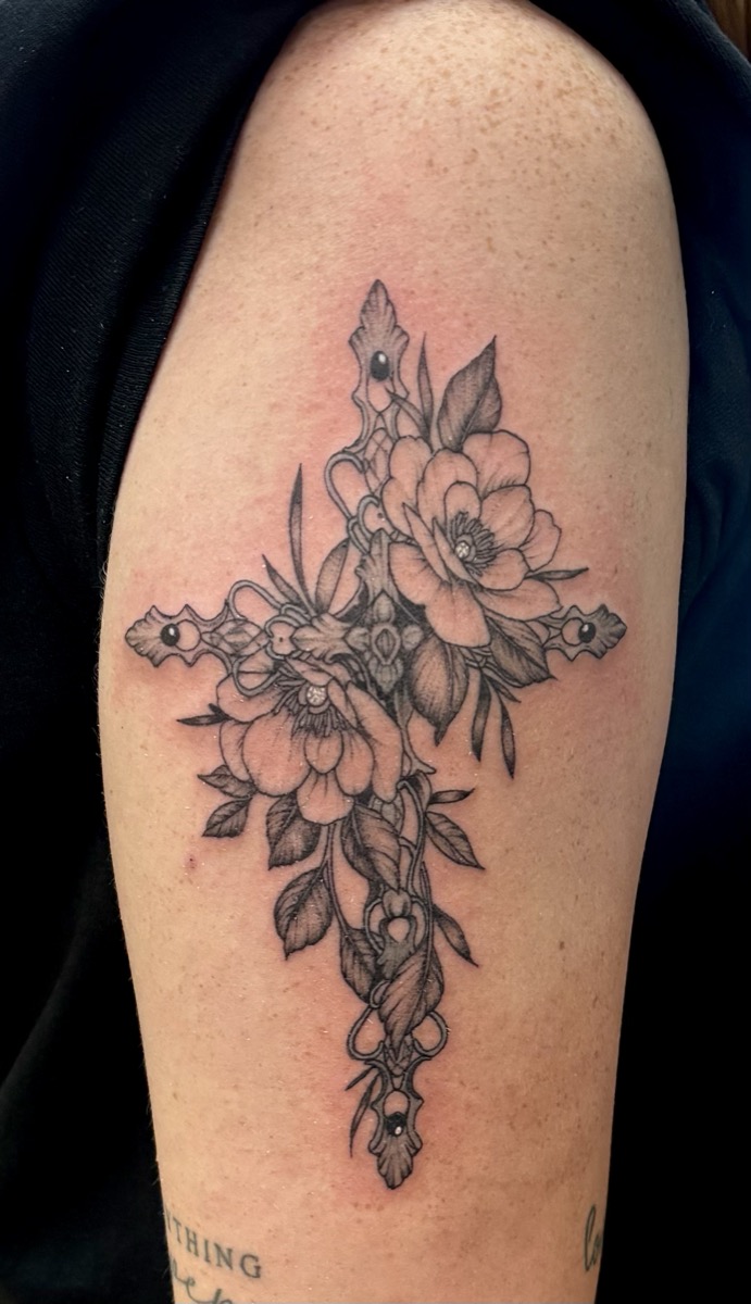 Ornate floral cross with peonies and trailing leaves on upper arm in black and grey